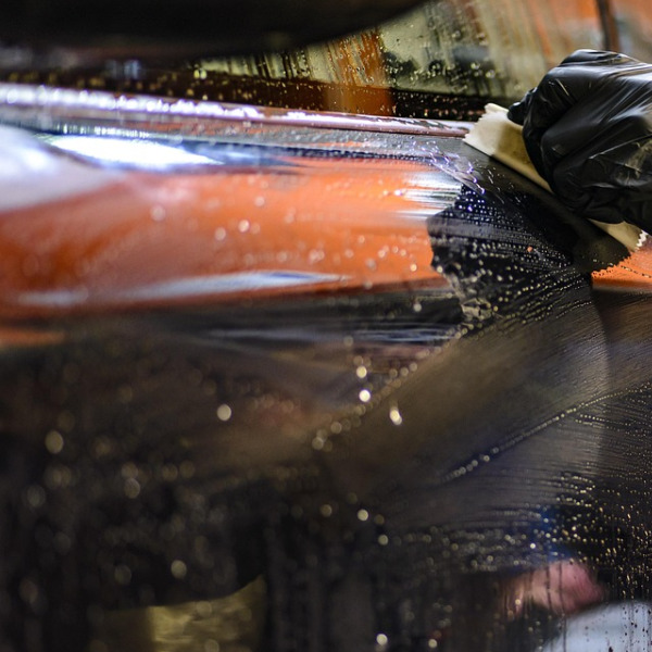 man drying polished car with microfiber towel